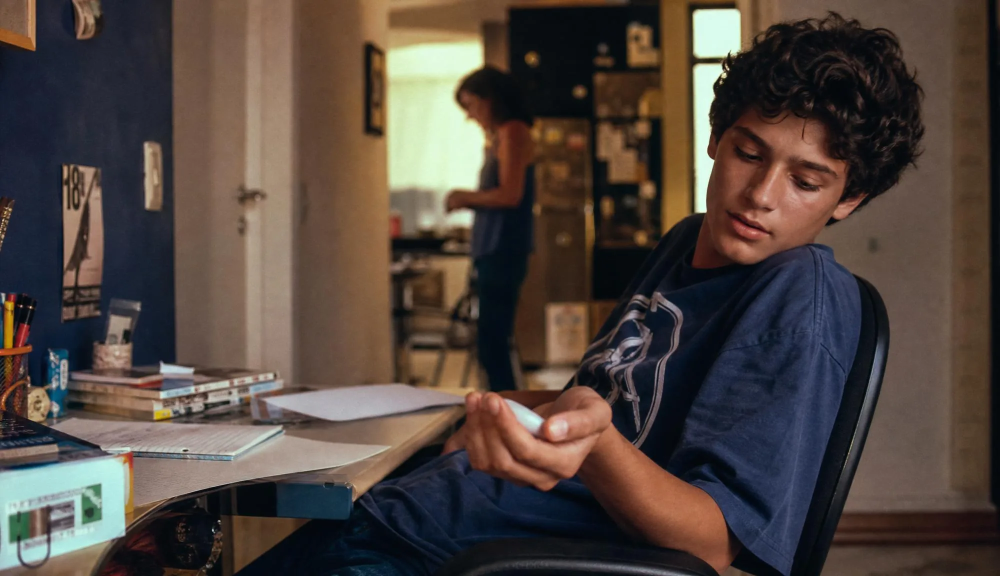 The teenager using the device beside schoolwork.